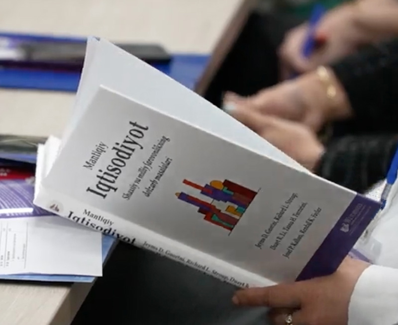 Common Sense Economics book open and being read by a person
