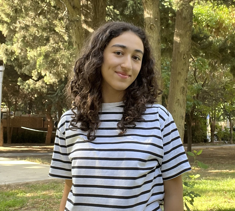 Student in stripey top smiling at camera