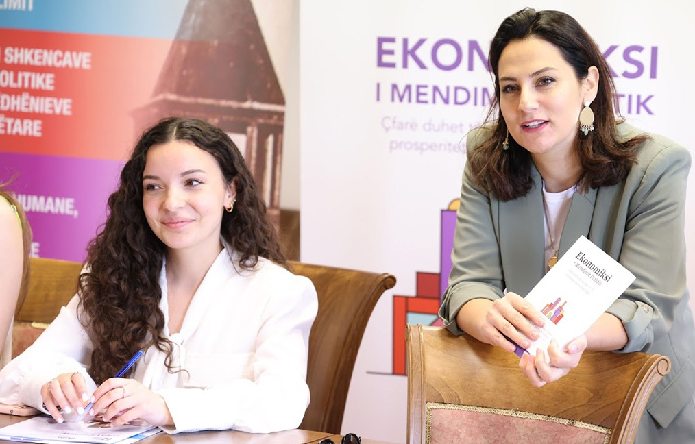 A trainer holding up the Common Sense Economics book as she engages with people in a workshop