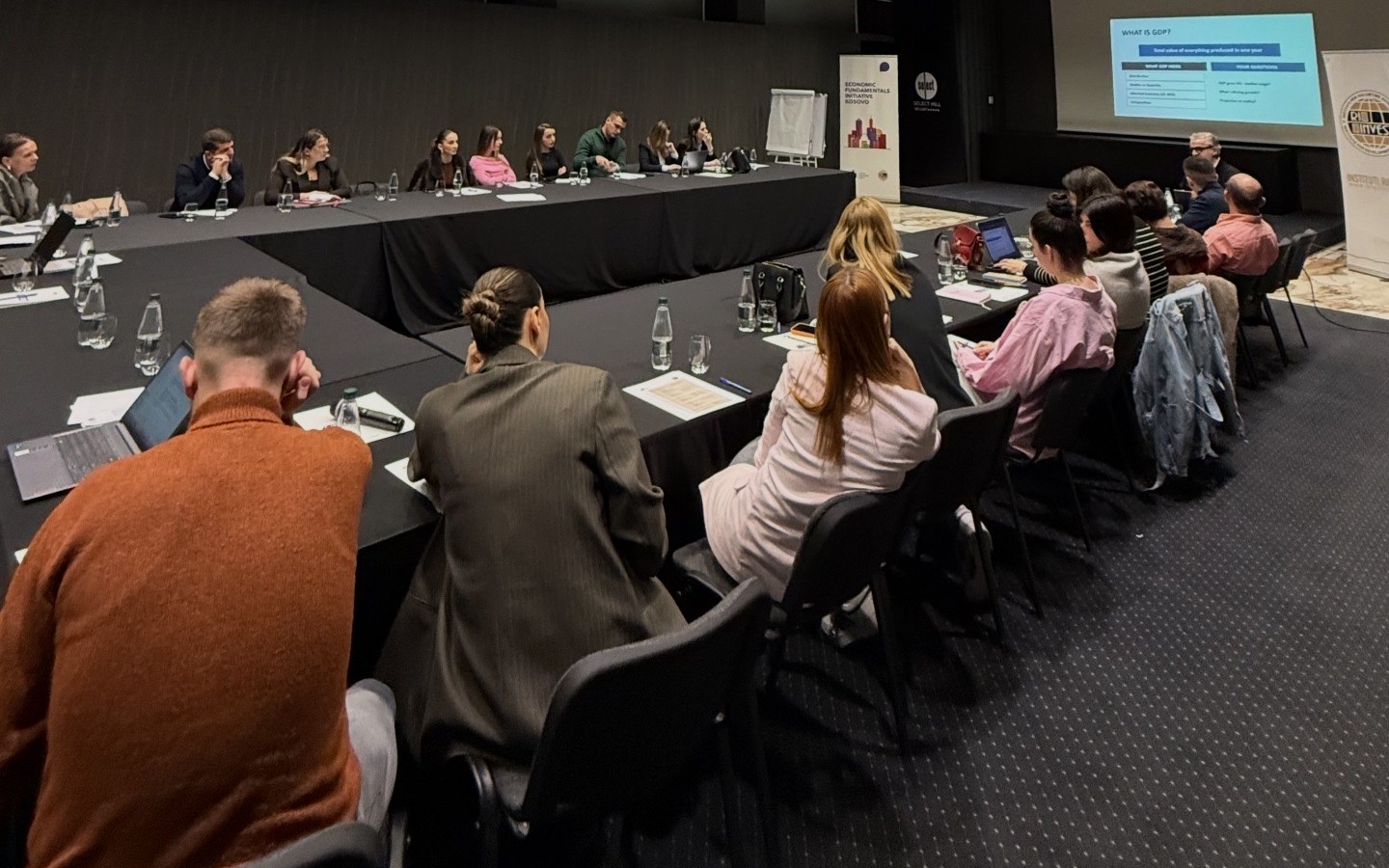 Event space with teachers sitting around a large table, all of them looking at a projector screen